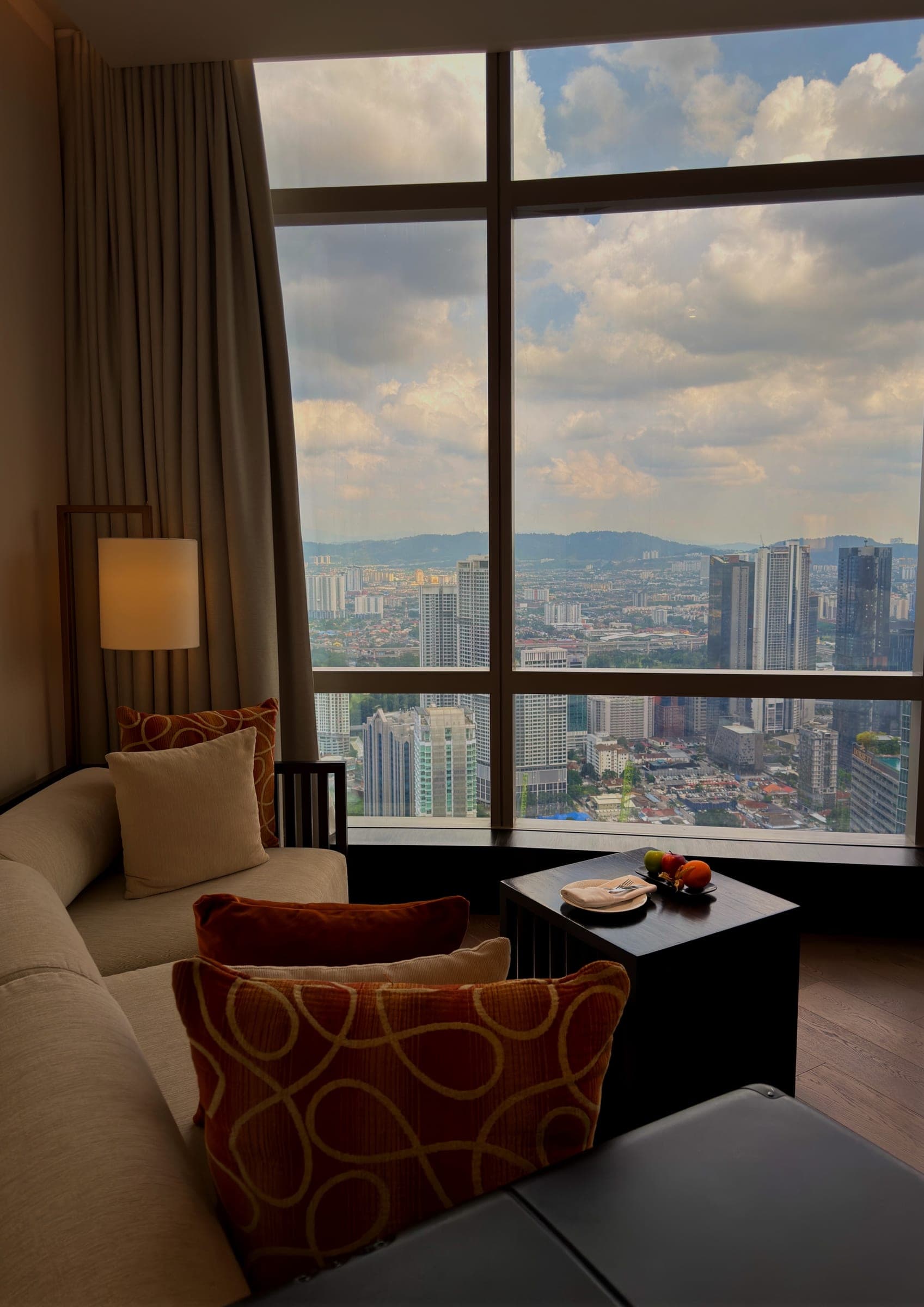 A sofa with amber cushions set into a corner window above the city