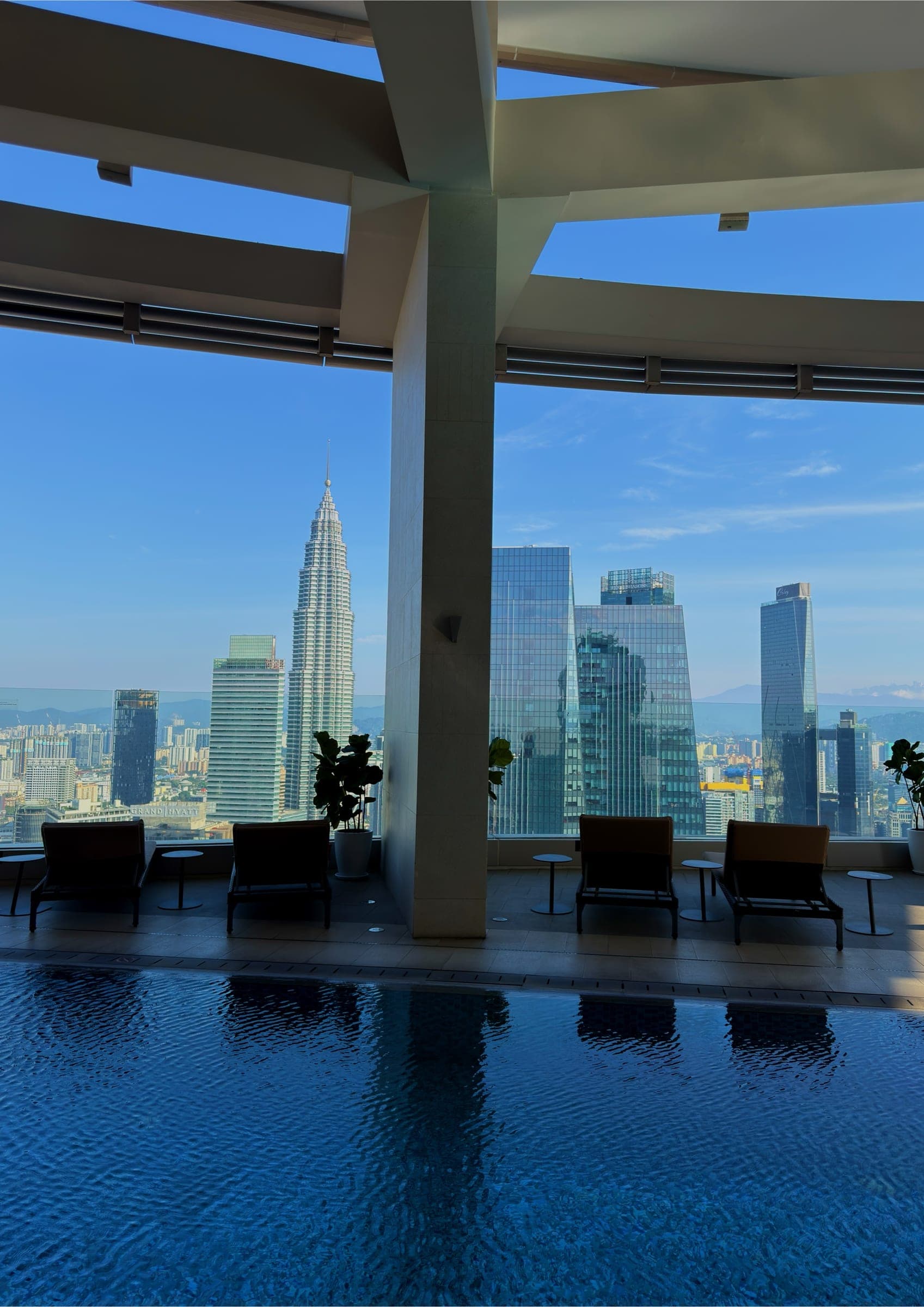 A pool with loungers looking out to the Petronas Twin Towers