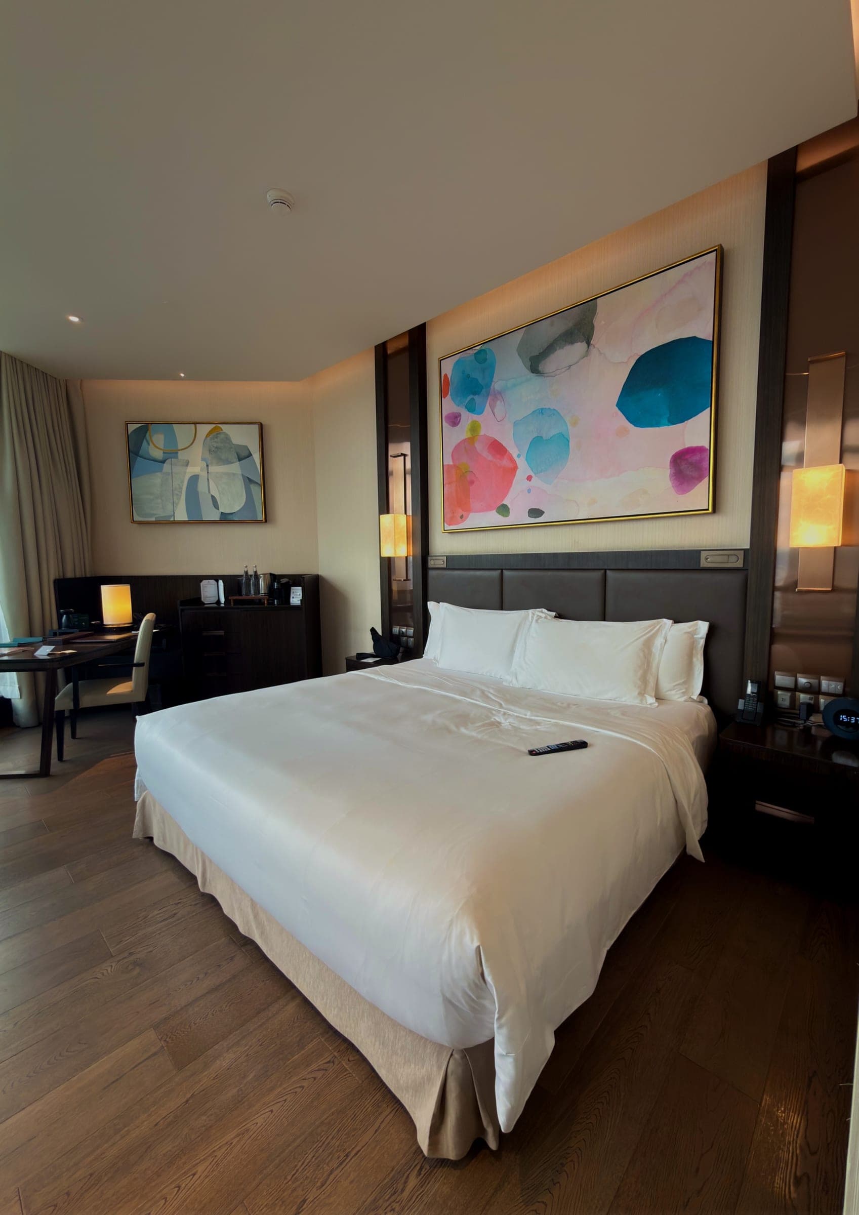 A guest room with a low bed and abstract art above the headboard