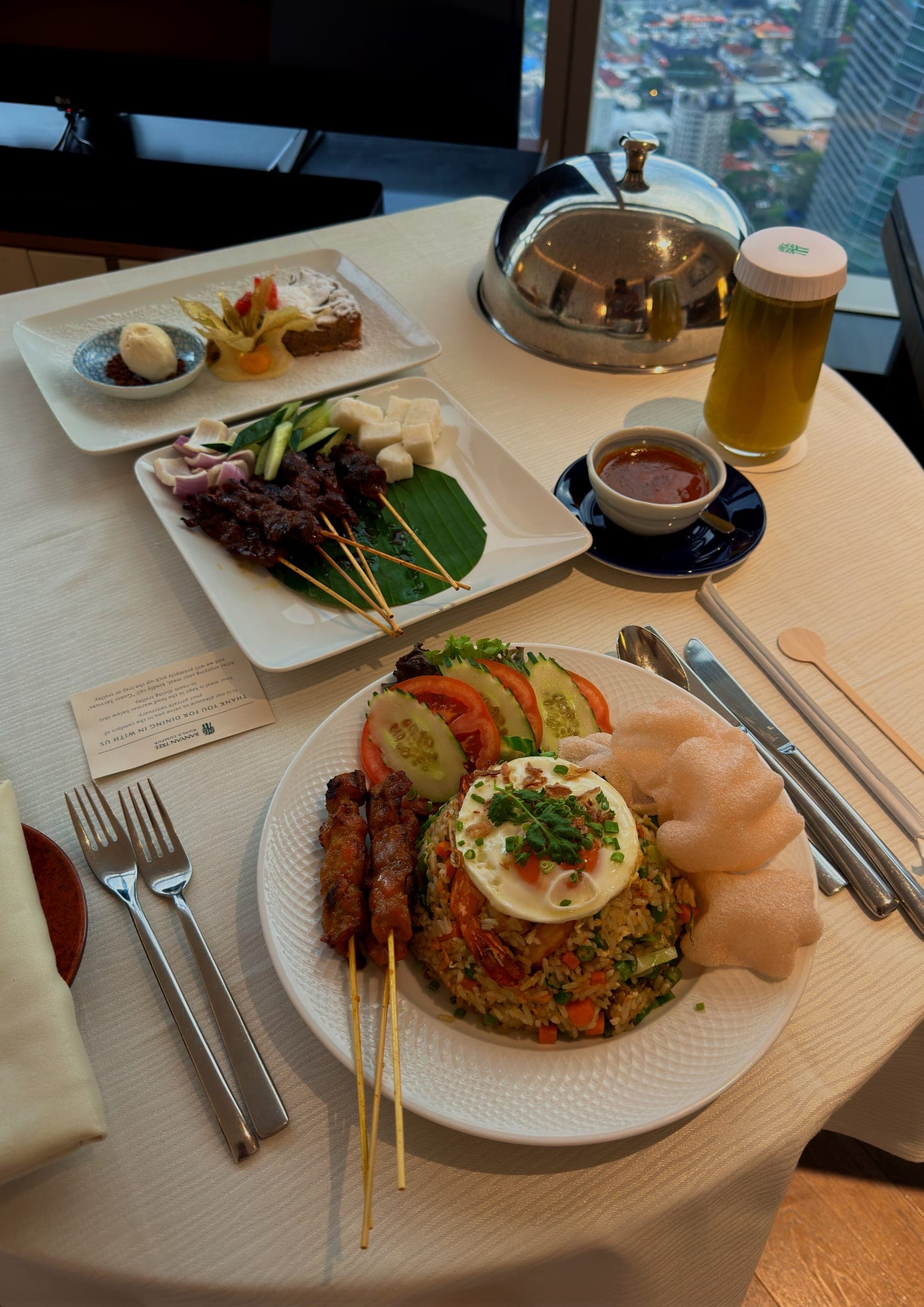 An in-room dining spread with a cloche, nasi goreng and drinks