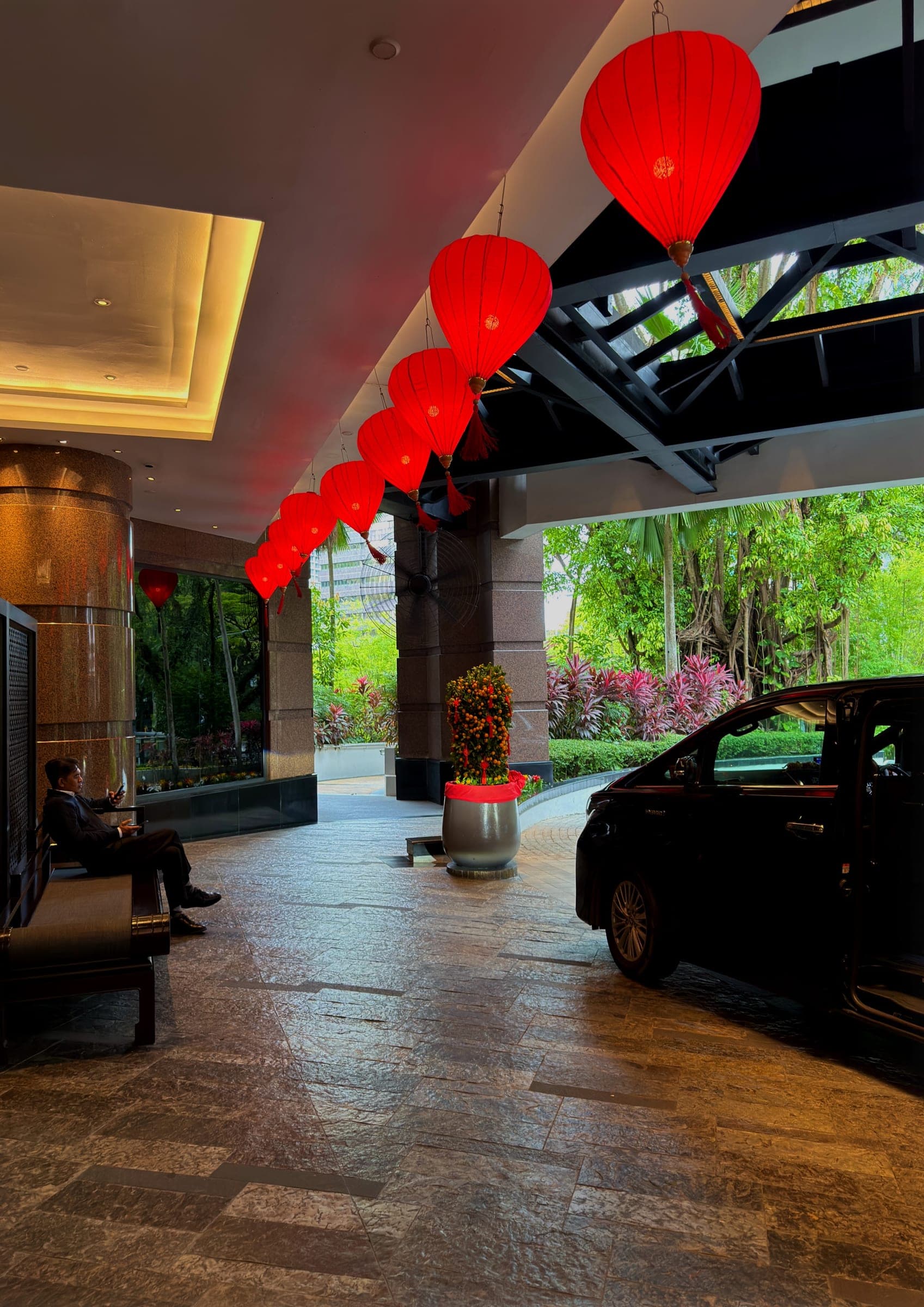 A porte-cochère hung with red lanterns and greenery beyond