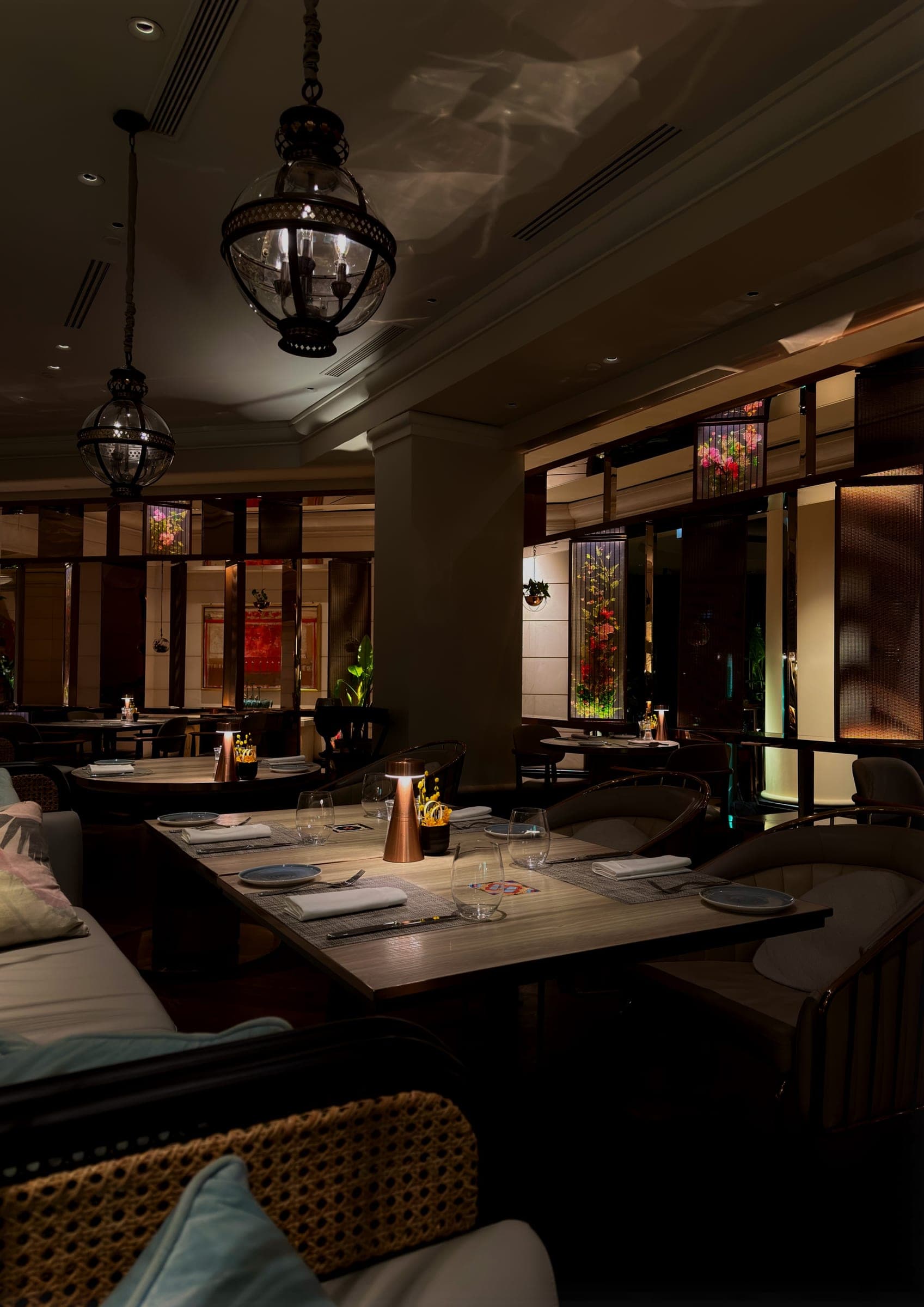 A dimly lit restaurant with hanging lanterns and floral panels