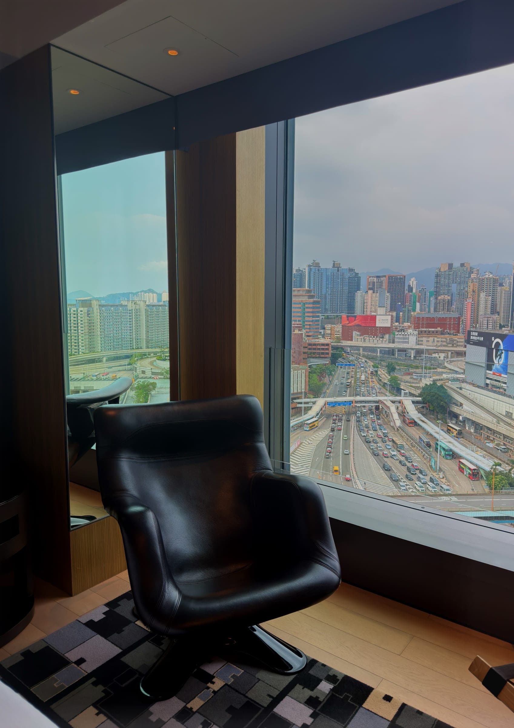A black leather chair set before a floor-to-ceiling window over Kowloon
