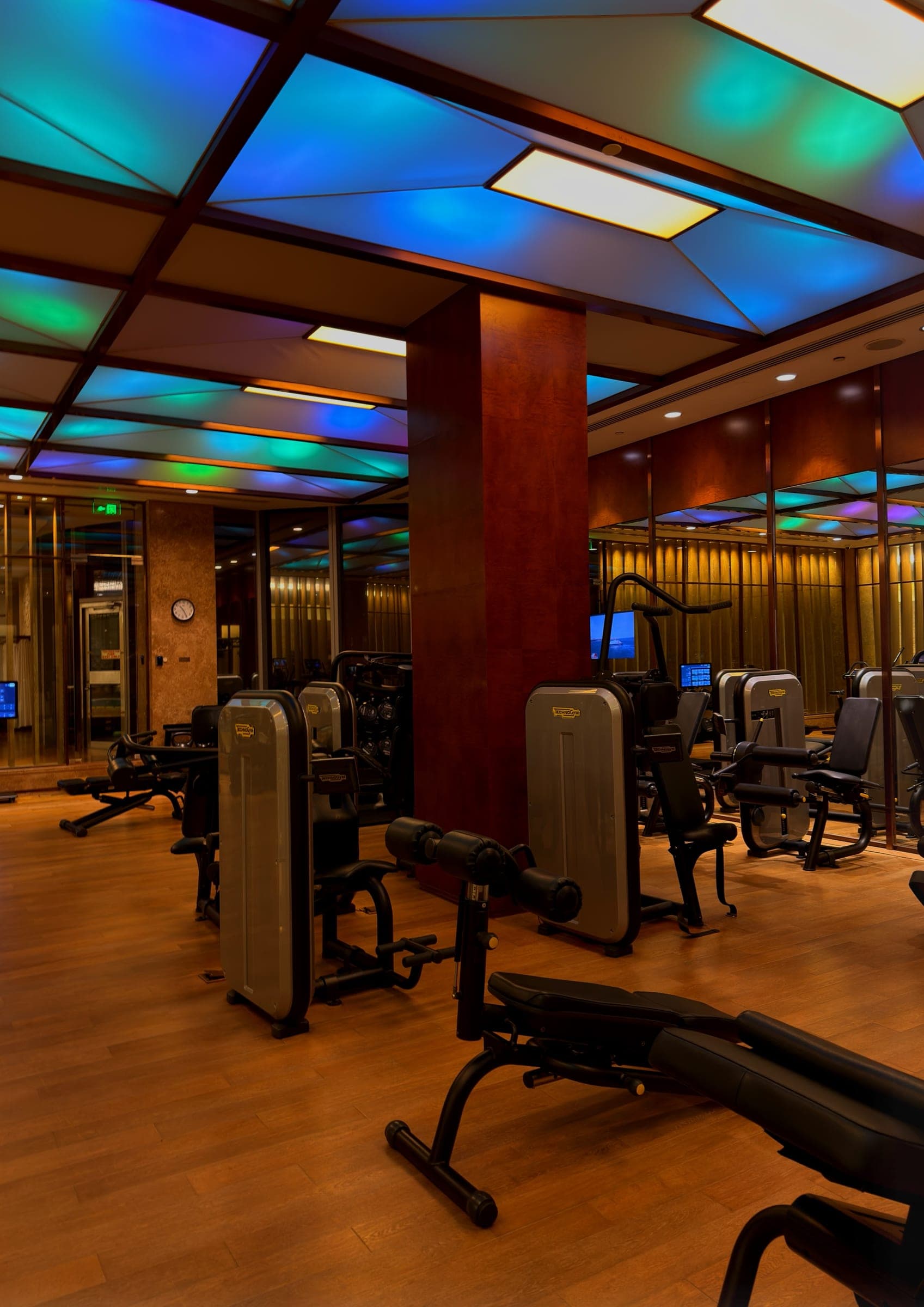 A gym with weight machines beneath a coloured glowing ceiling