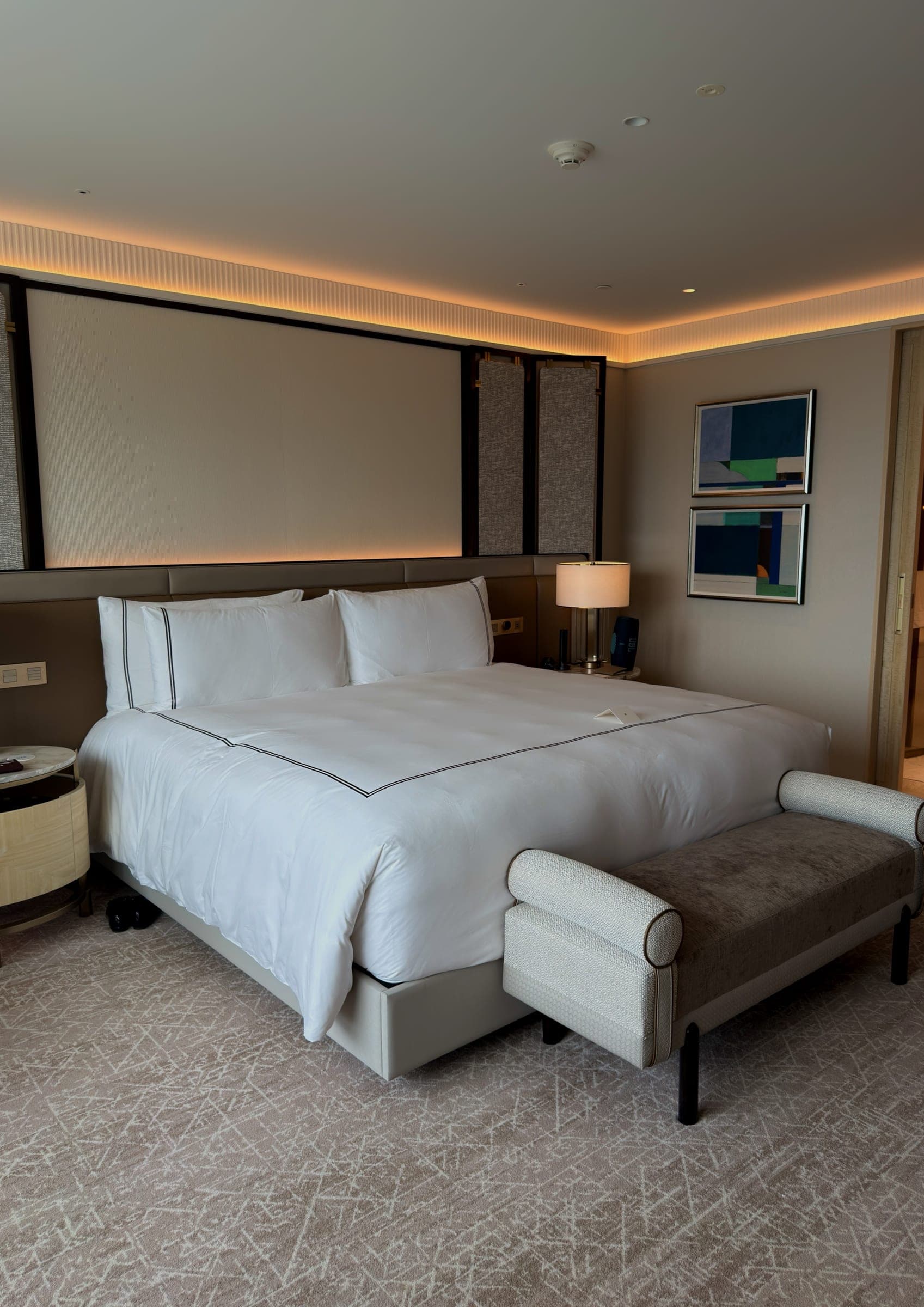 A king bed dressed in white linen in a modern guest room