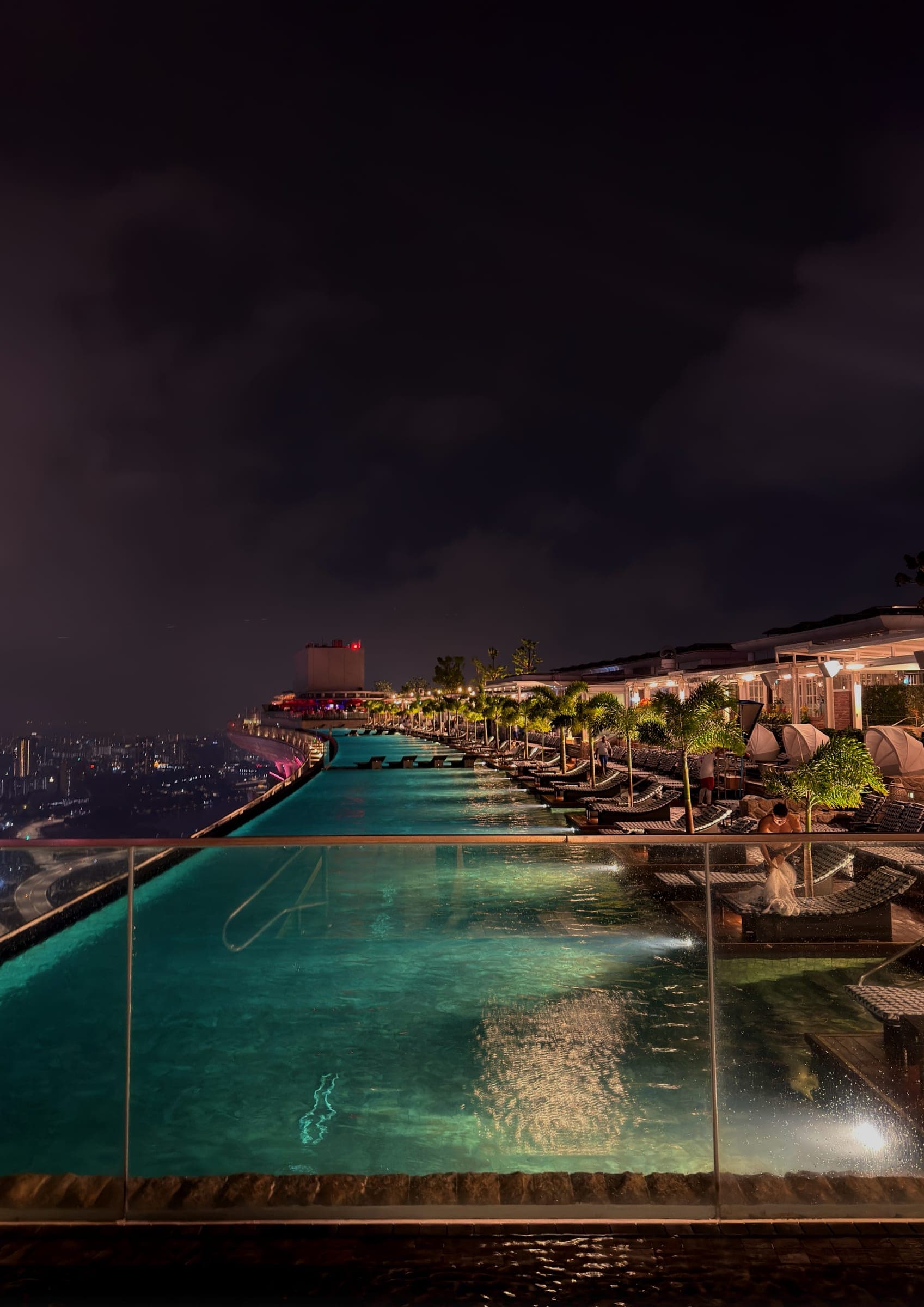 The rooftop infinity pool lit against the night sky