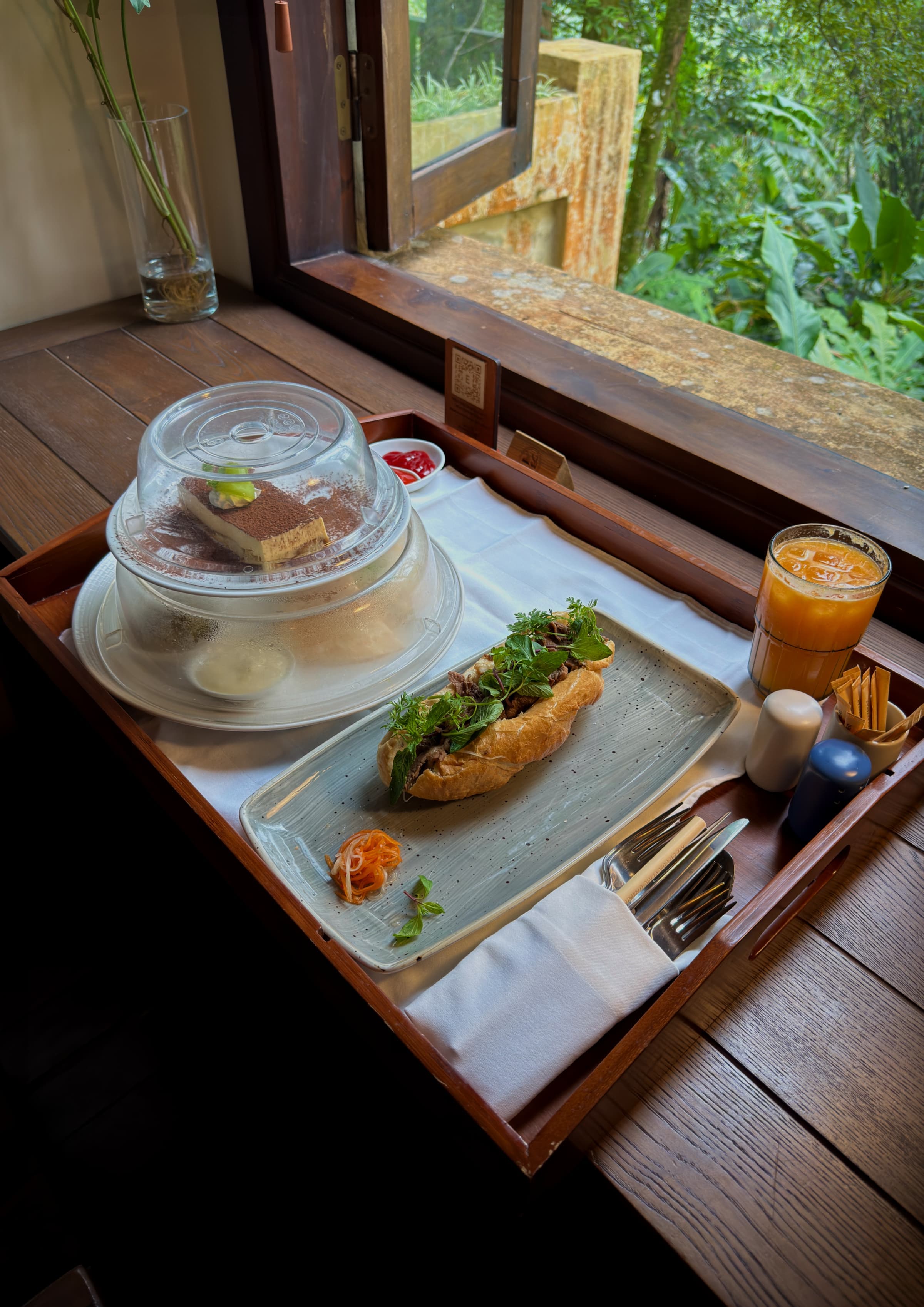 A breakfast tray set by a window looking out into the forest
