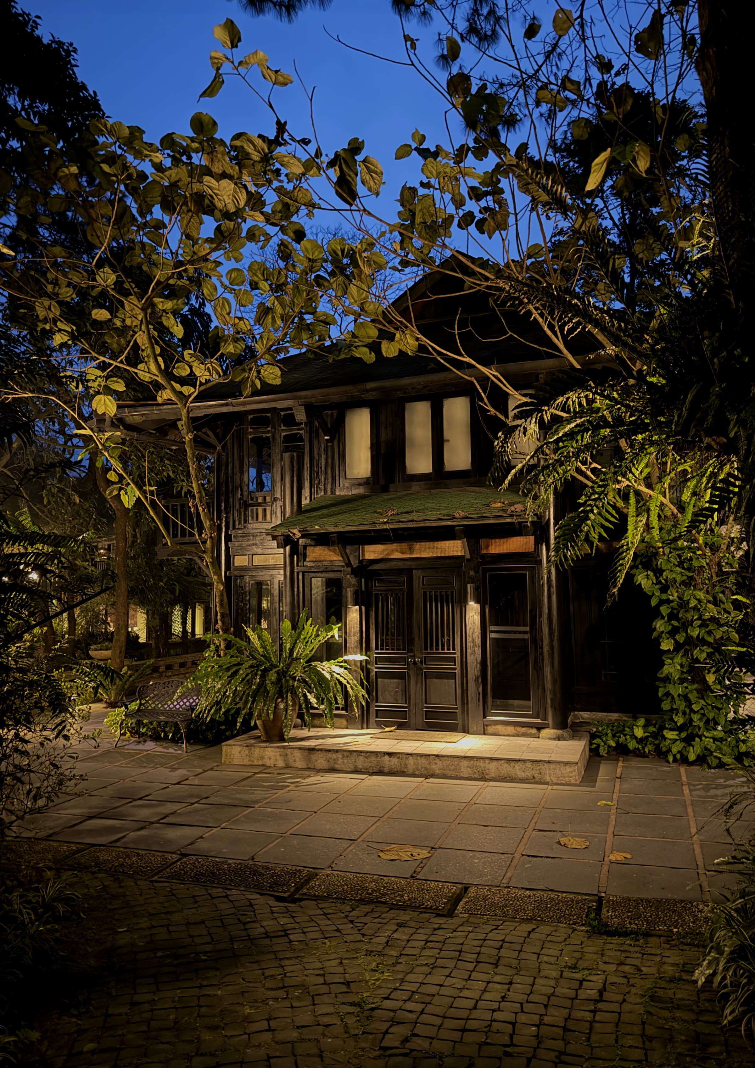 The wooden buildings of the retreat lit at dusk on a stone path