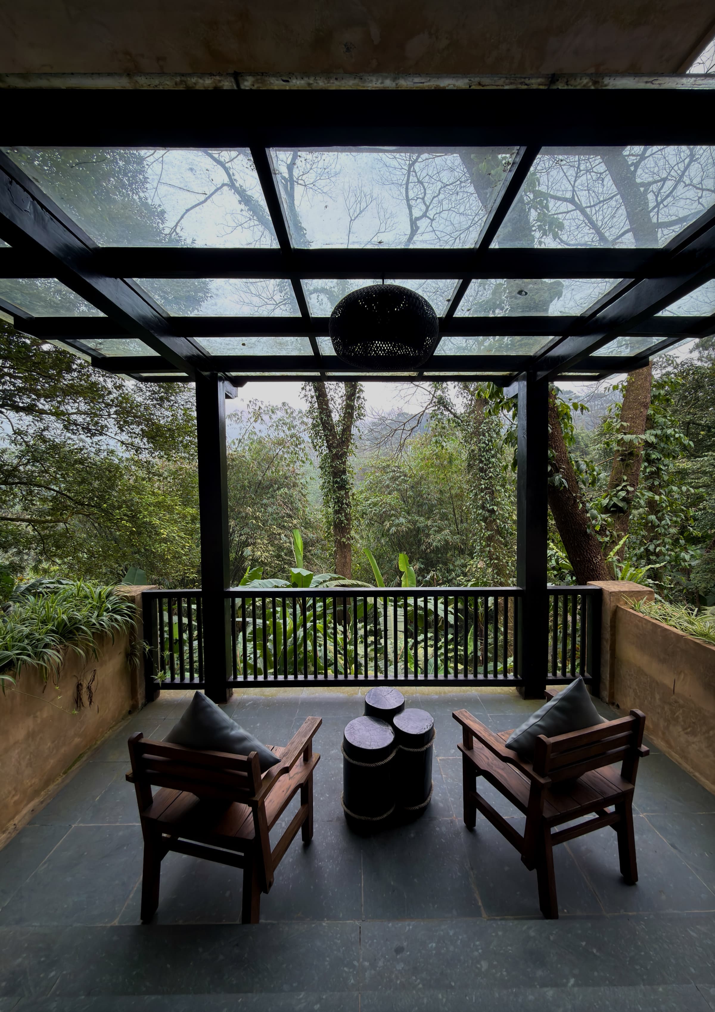 A covered wooden balcony with chairs looking out into misty forest