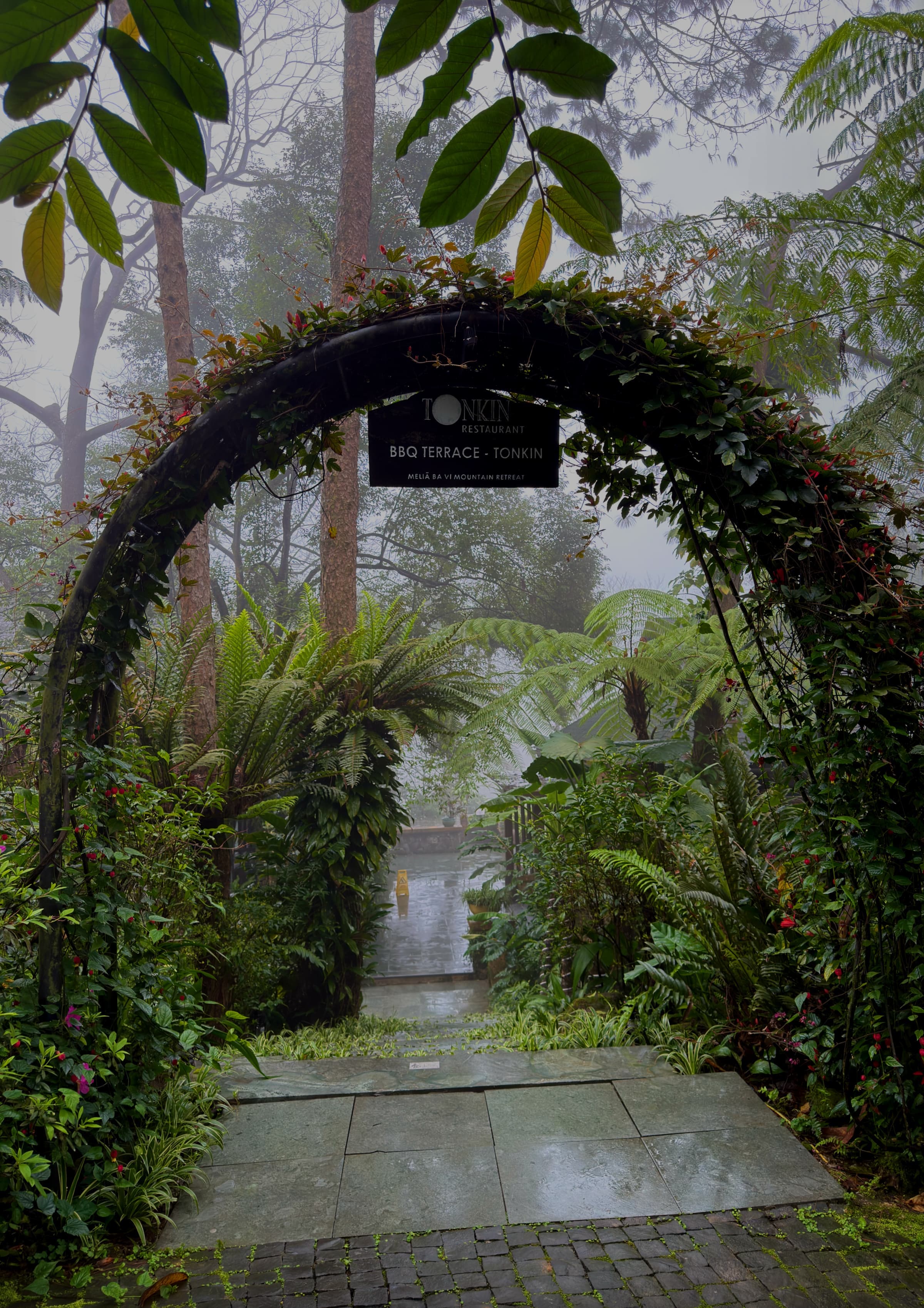 A circular stone moon gate opening onto a path through the retreat’s forest gardens