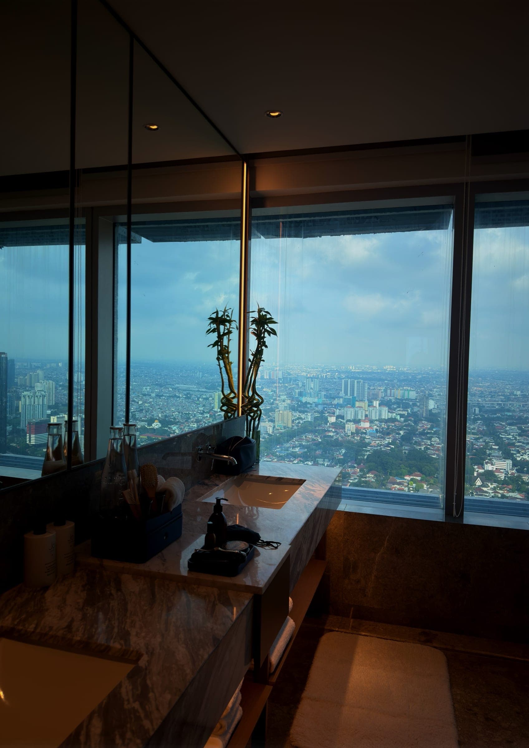 A marble vanity set against floor-to-ceiling windows over Jakarta