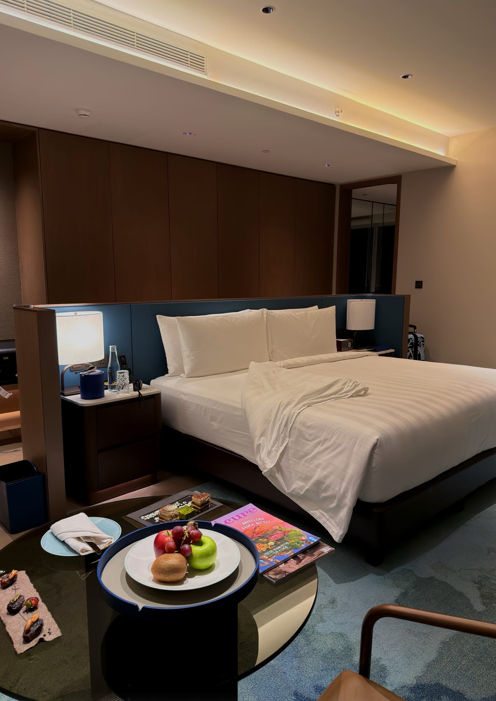 A bed against a timber headboard with a fruit plate on the table