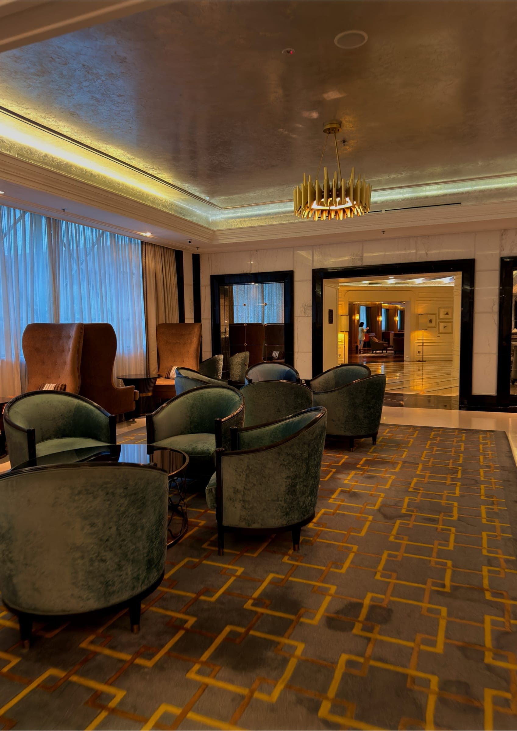 A lounge of green velvet chairs on a patterned carpet