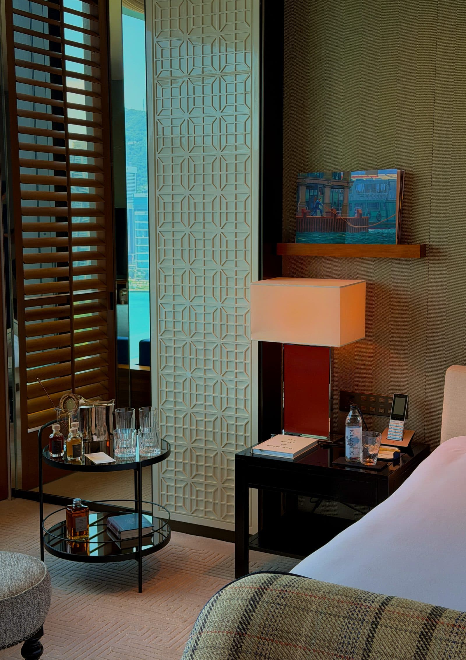 A bedside lamp above a small drinks table set in the corner
