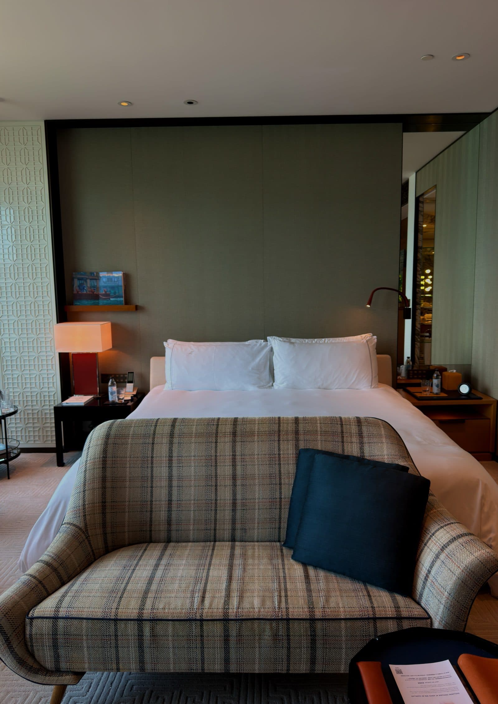 A made bed with an armchair set beside it
