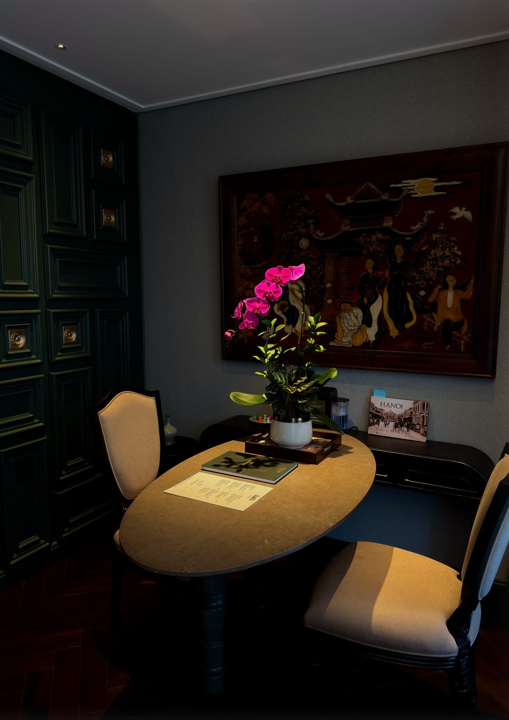 A writing desk with an orchid and a lacquer panel of a Vietnamese scene above