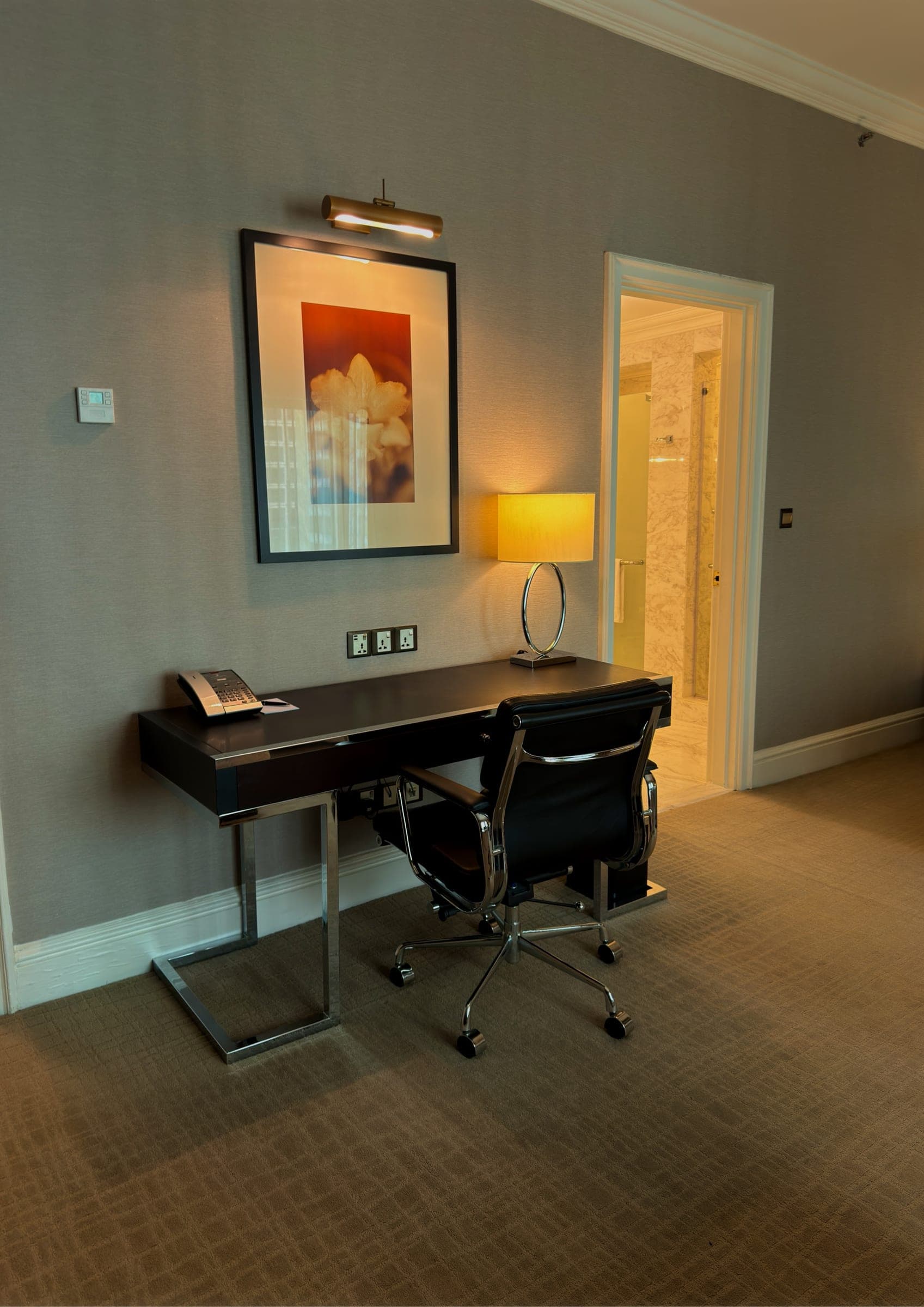 A dark timber writing desk with framed artwork above